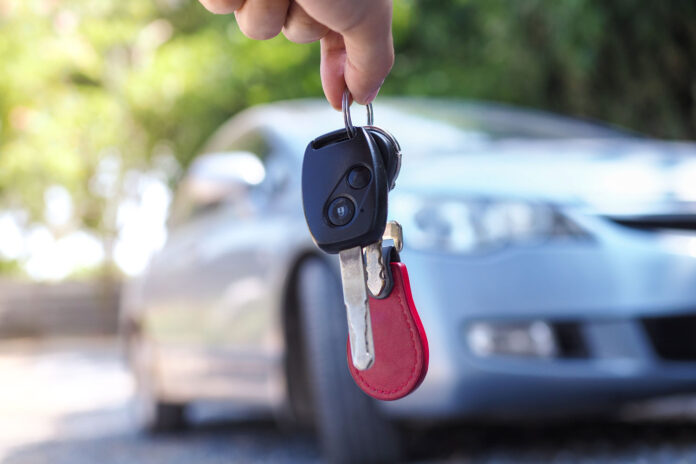 The car owner is standing the car keys to the buyer. Used car sales